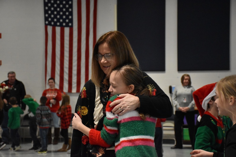 Former Elementary School Principal Kelly Beitz gives one of her students a hug during her surprise send-off assembly in December. 