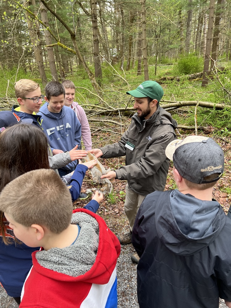 Middle school students touch an animal hide offered by Environmental Educator Conrad Baker during a field trip to Letchworth State Park Monday. 