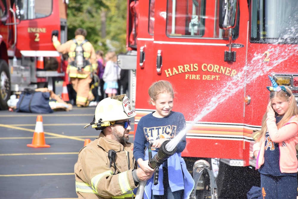 A Harris Corners firefighter helps an Attica Elementary School student use a handline during Fire Prevention Day Oct. 6.