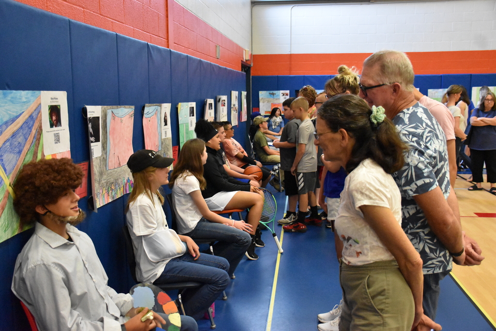 Sixth graders are shown presenting their biography research products during their Wax Museum in the Middle School Gymnasium. 