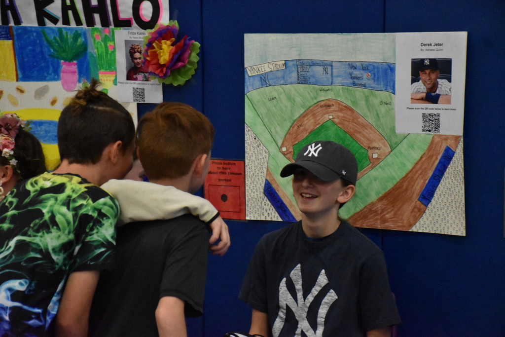 Sixth graders are shown presenting their biography research products during their Wax Museum in the Middle School Gymnasium. 